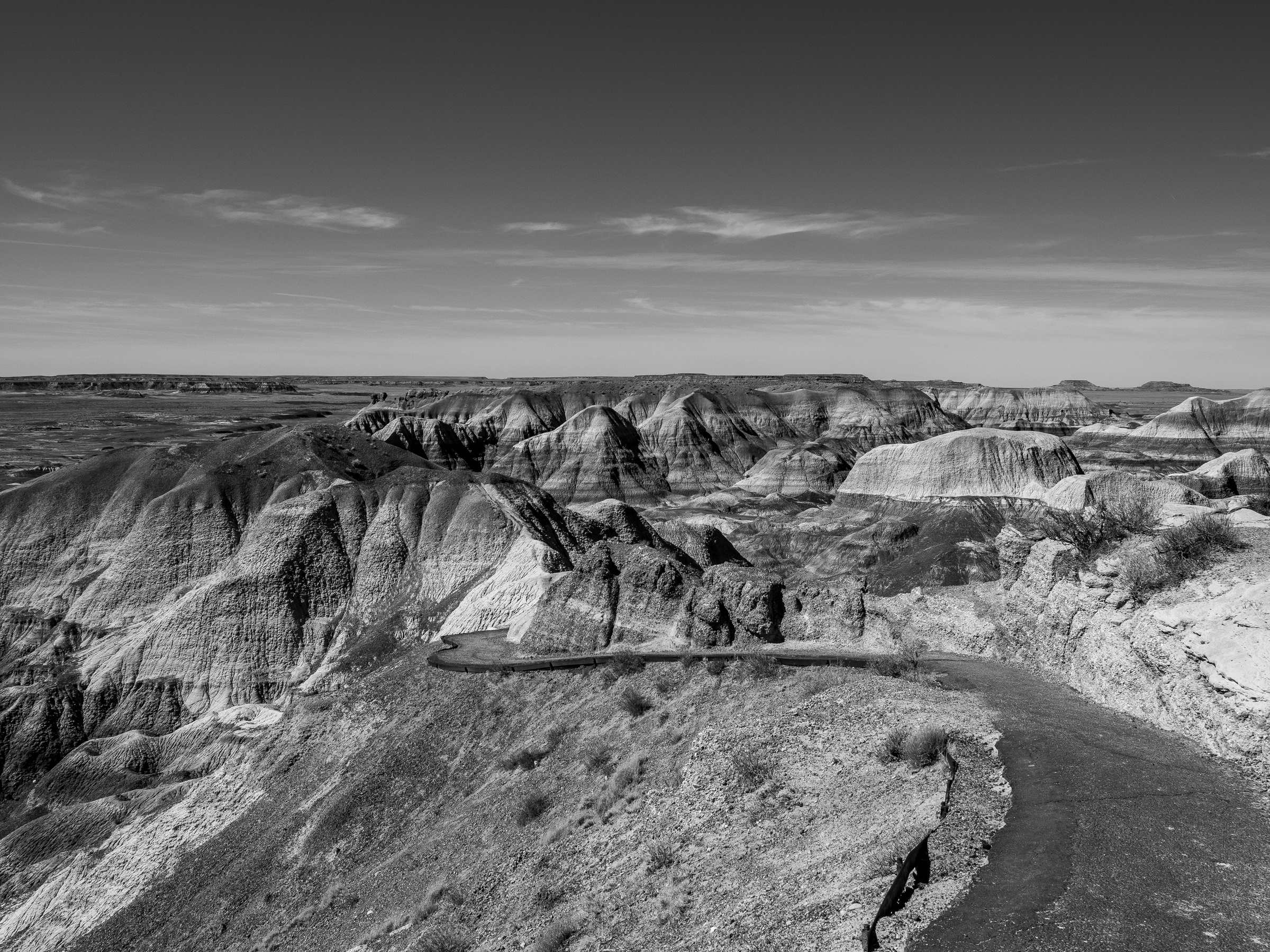 Badlands National Park’s eroded, colorful rock formations stretch across a vast landscape under a cloudy sky.