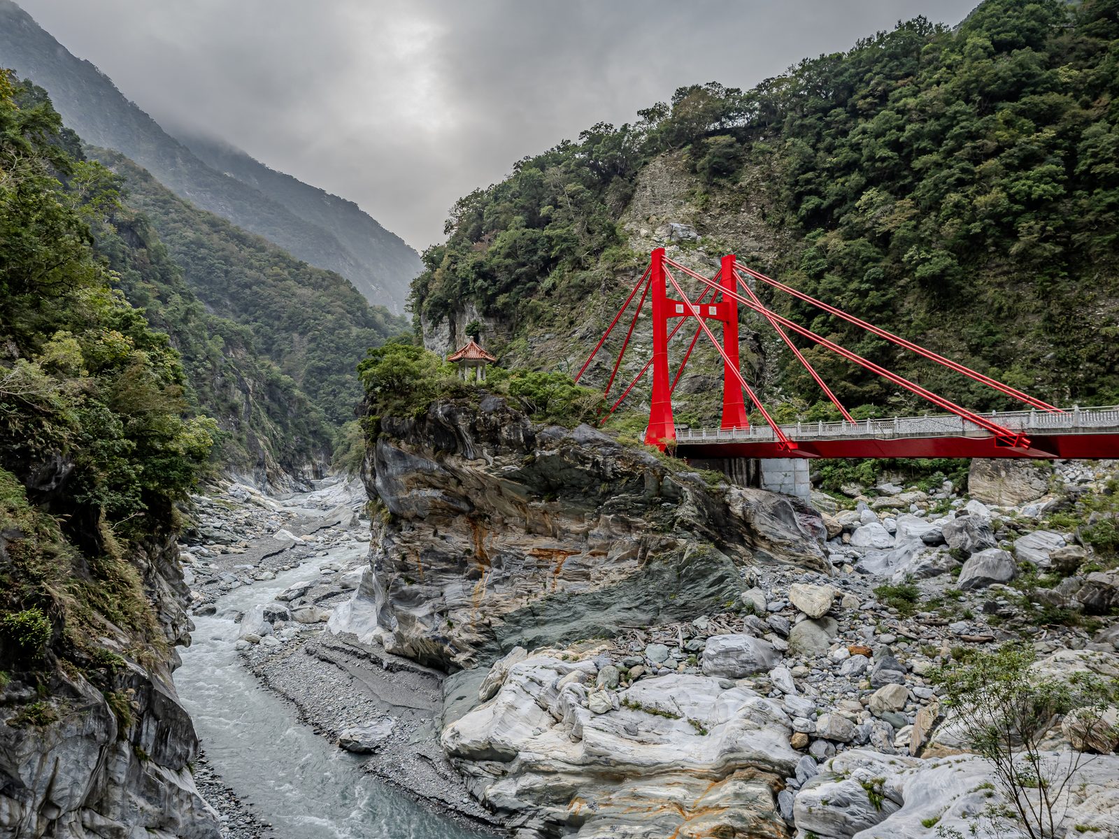 A red bridge through a mountain valley.