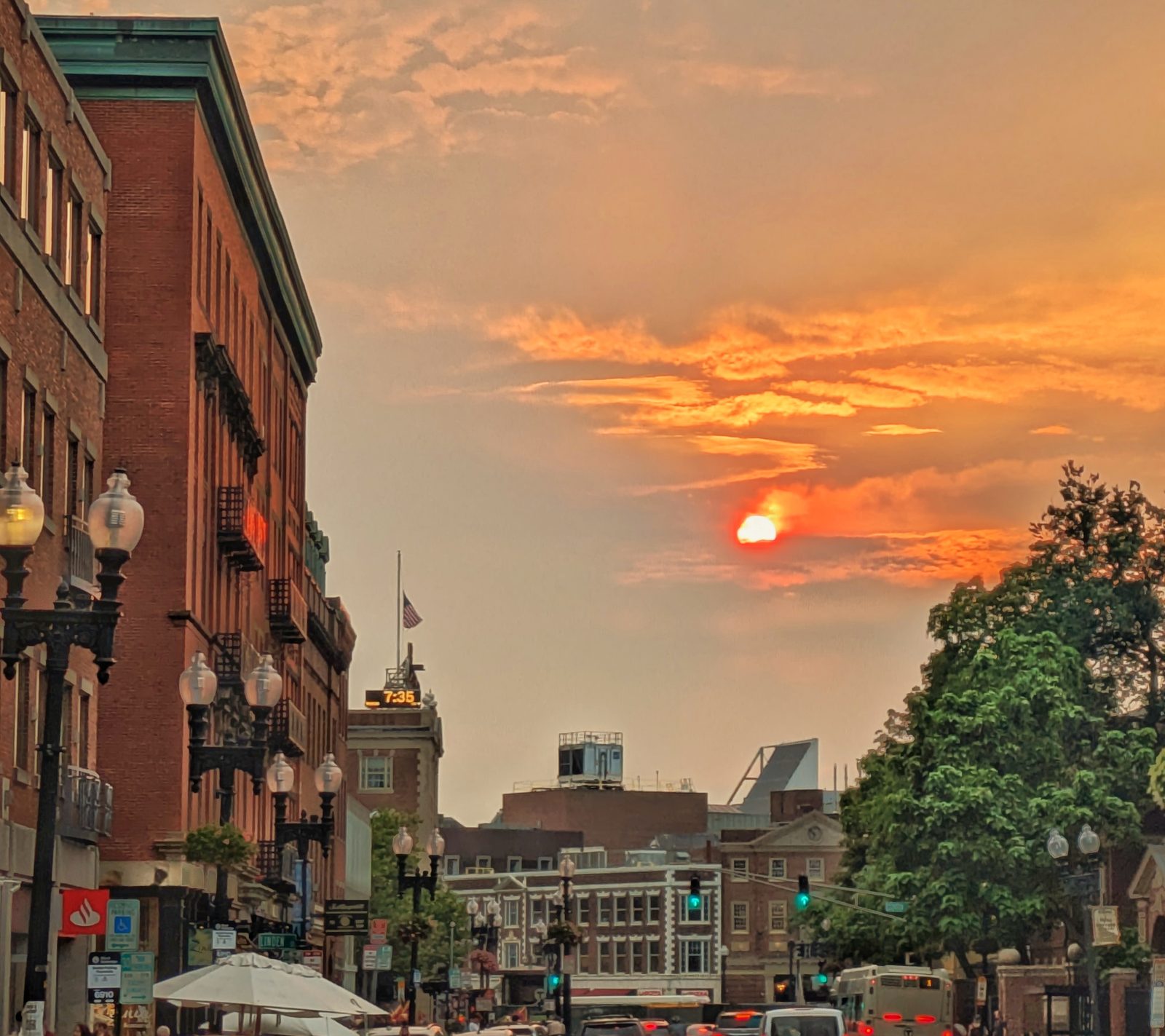 A city street with brick buildings under a vibrant orange sunset sky.