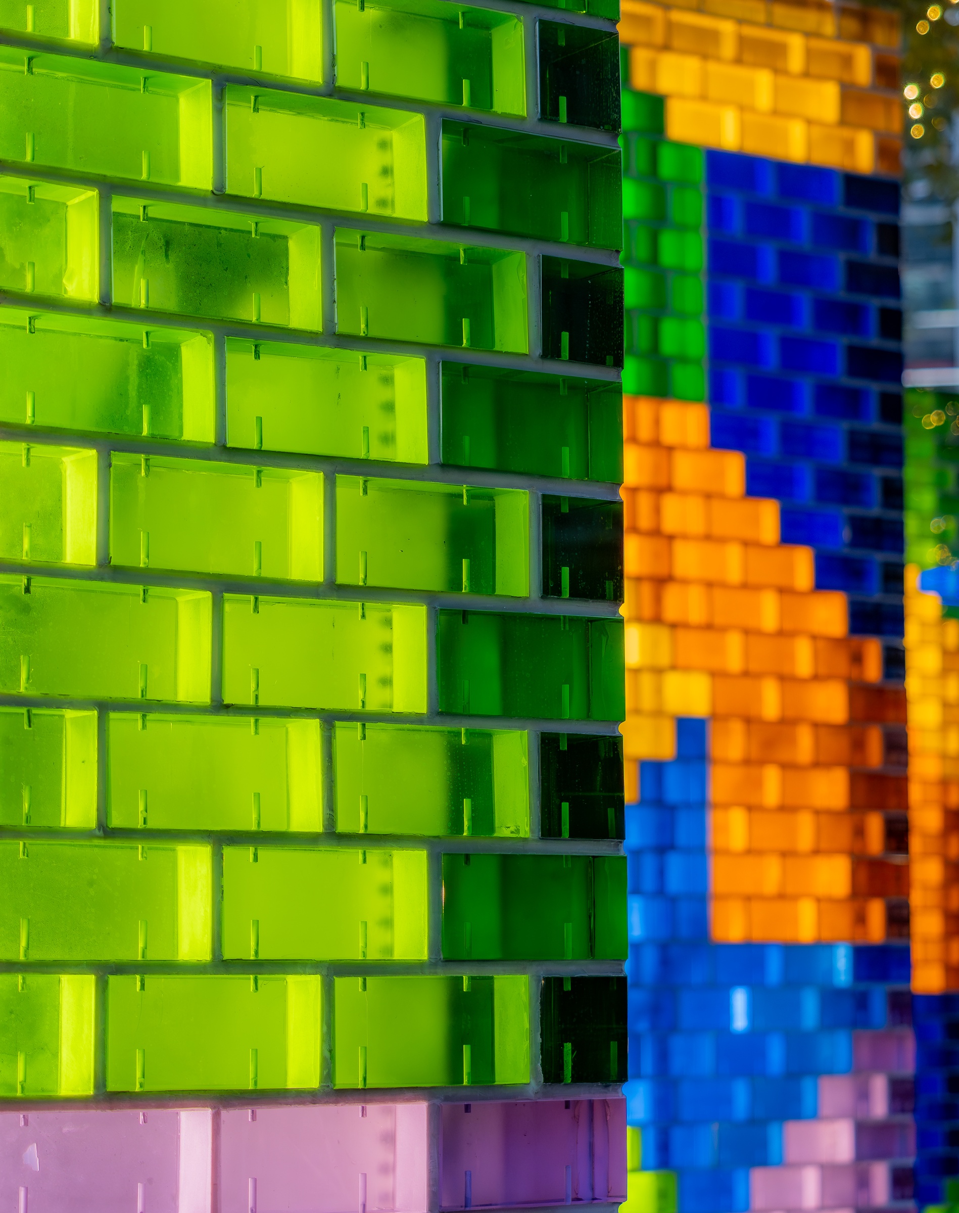 Colorful glass brick columns form a vibrant, abstract pattern against a blurred background.