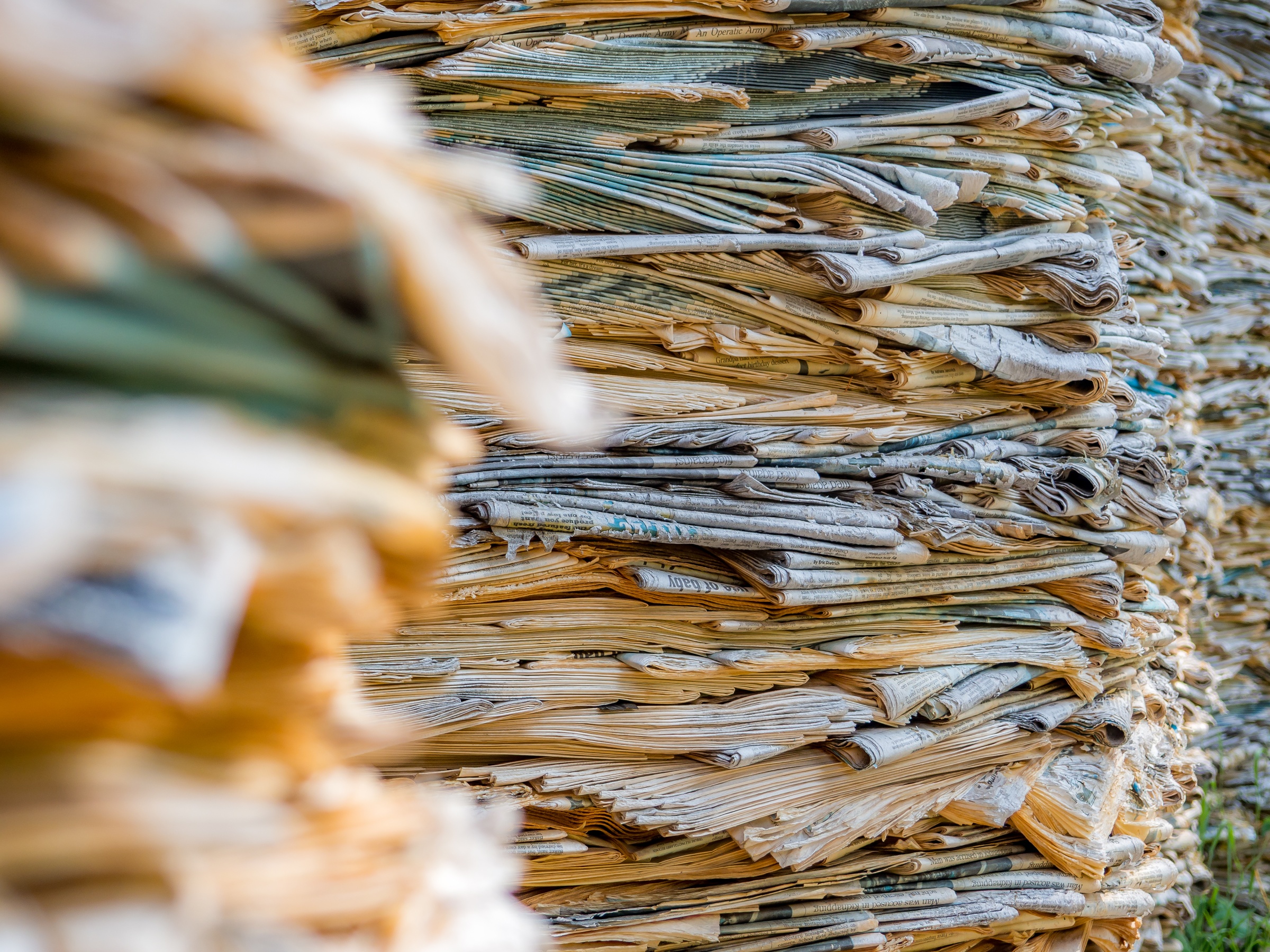 Stacked, dried banana leaves form a textured, layered pile in an outdoor setting.