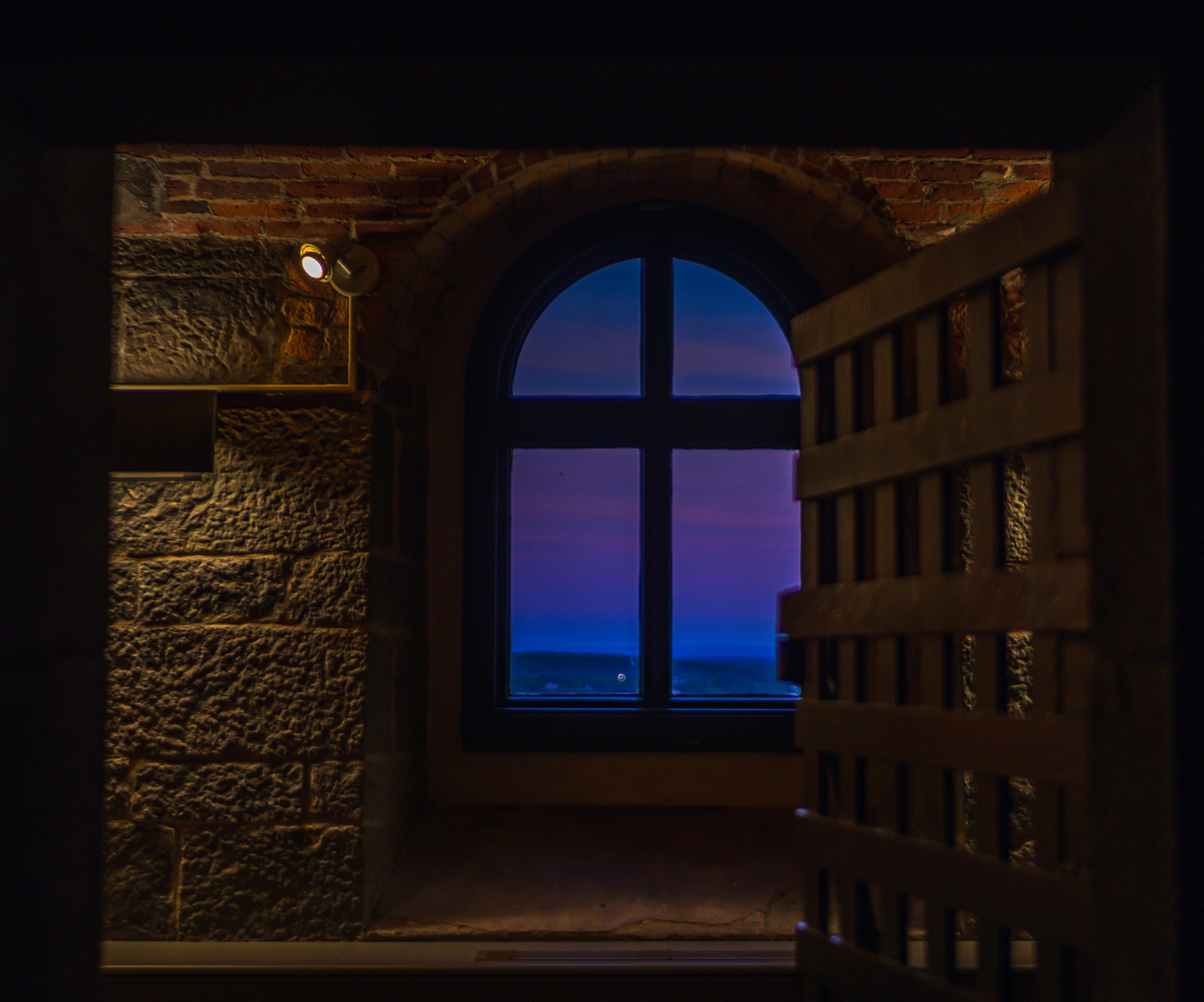 An open doorway frames a window overlooking a twilight sky and distant lights.