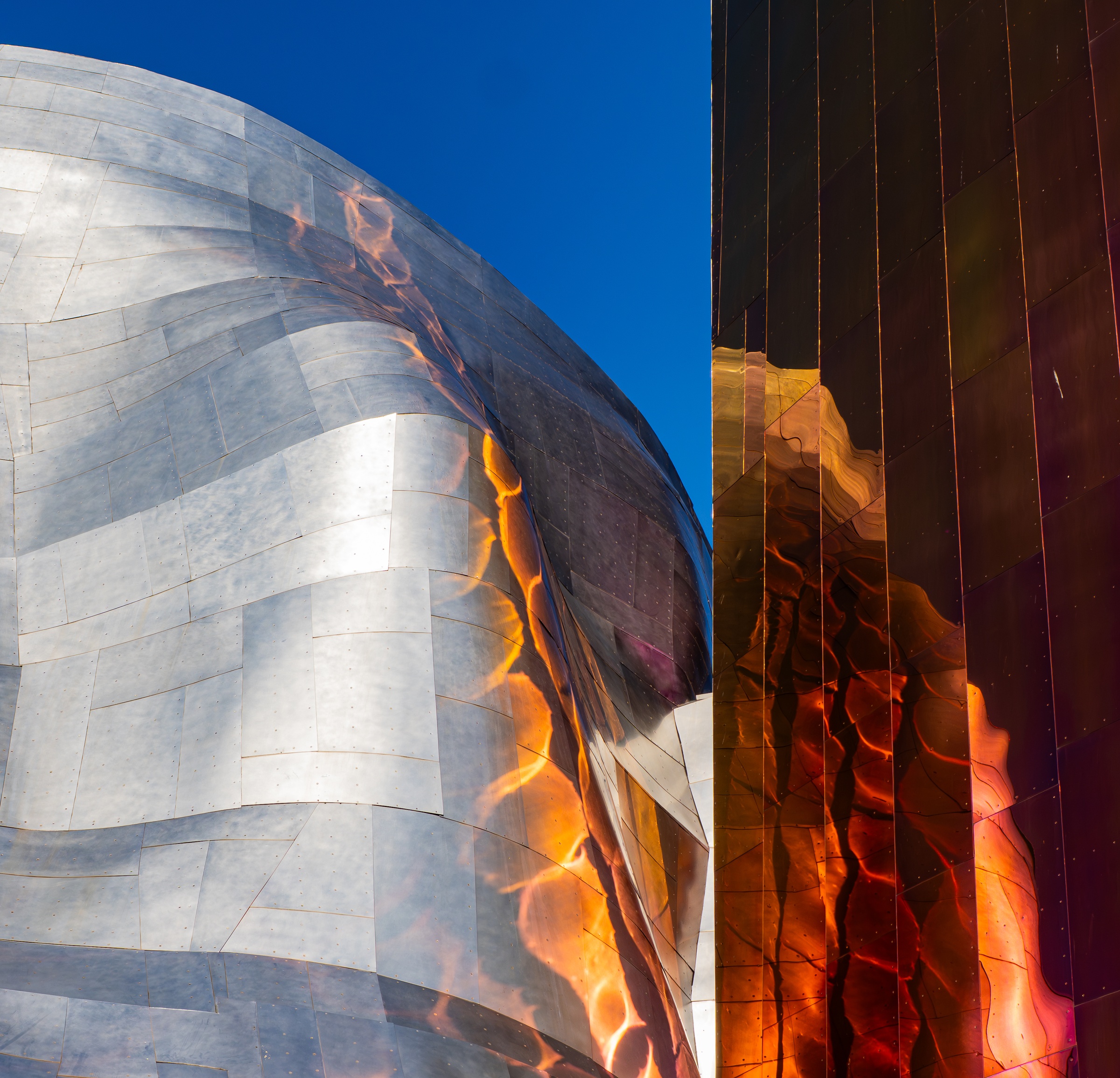 Silver and copper-colored metal panels curve against a bright blue sky at the Museum of Pop Culture.