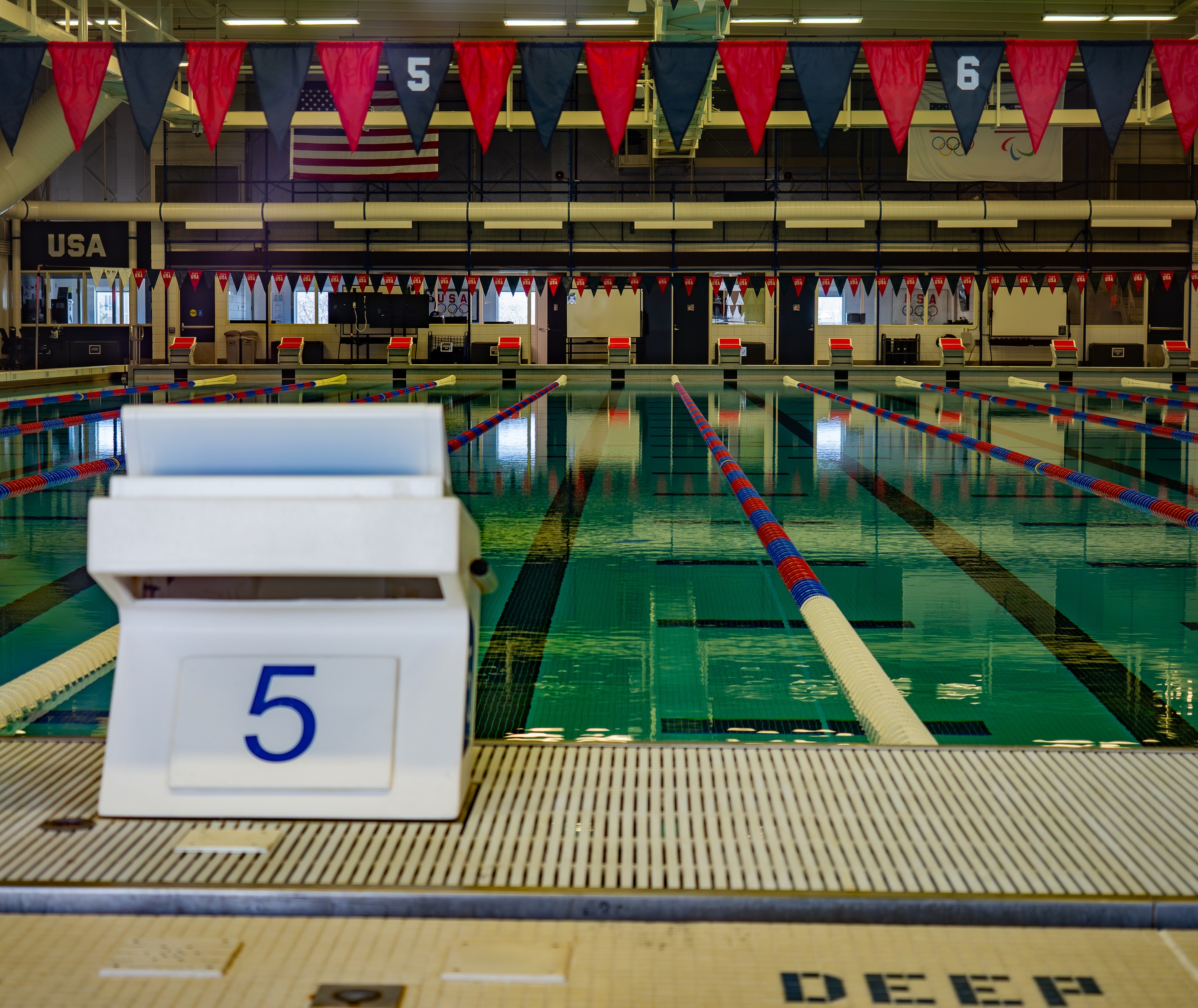 An indoor swimming pool with lane markers and a numbered starting block is visible.