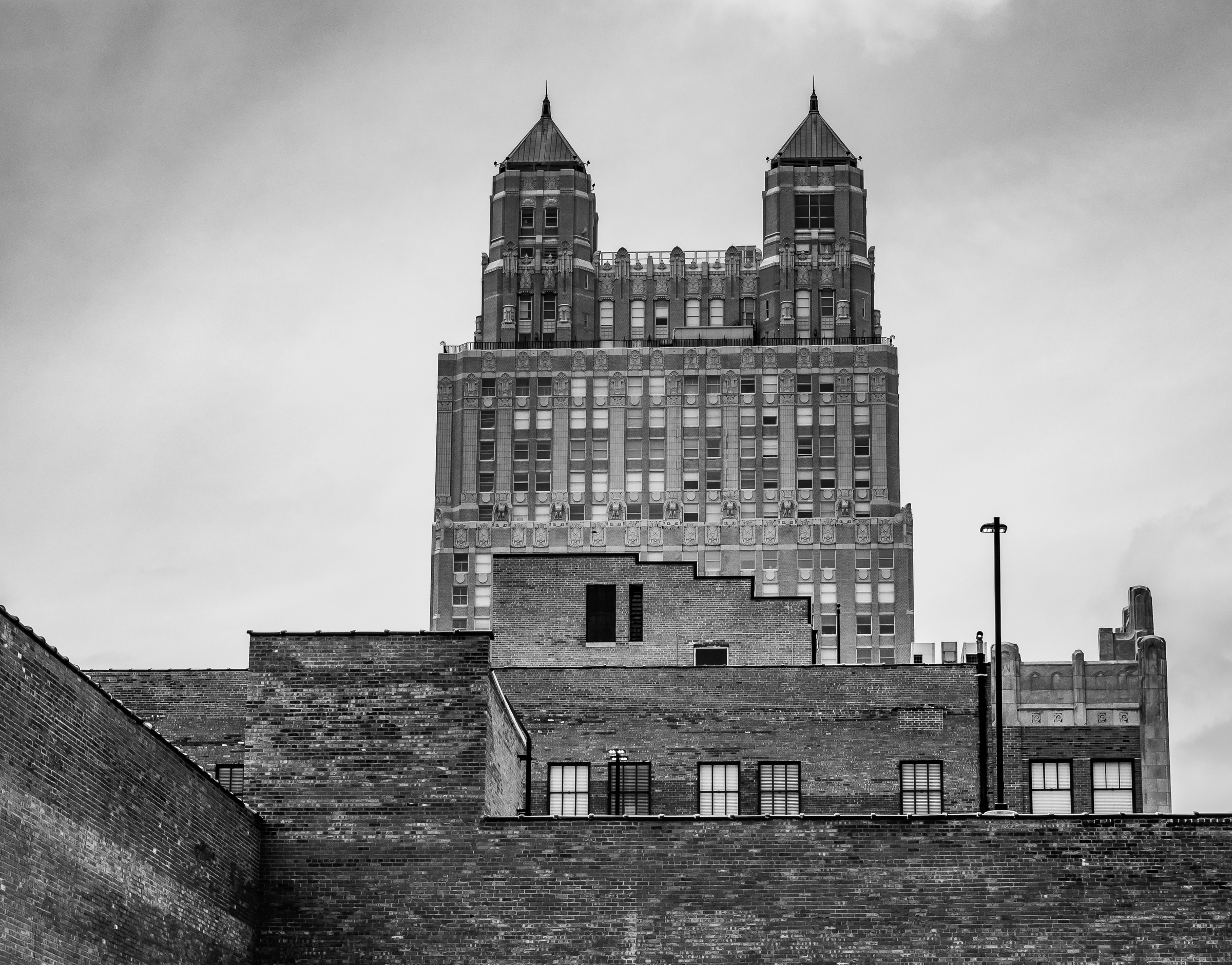 A black and white photograph shows a large ornate building with two towers against a cloudy sky.