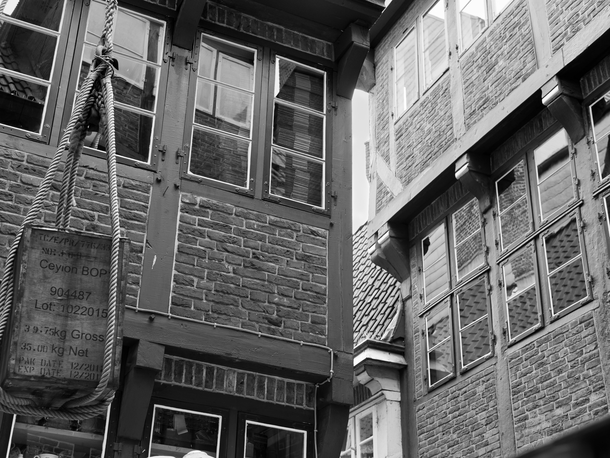 A rope and sign hang in front of a tall, narrow brick building with windows.