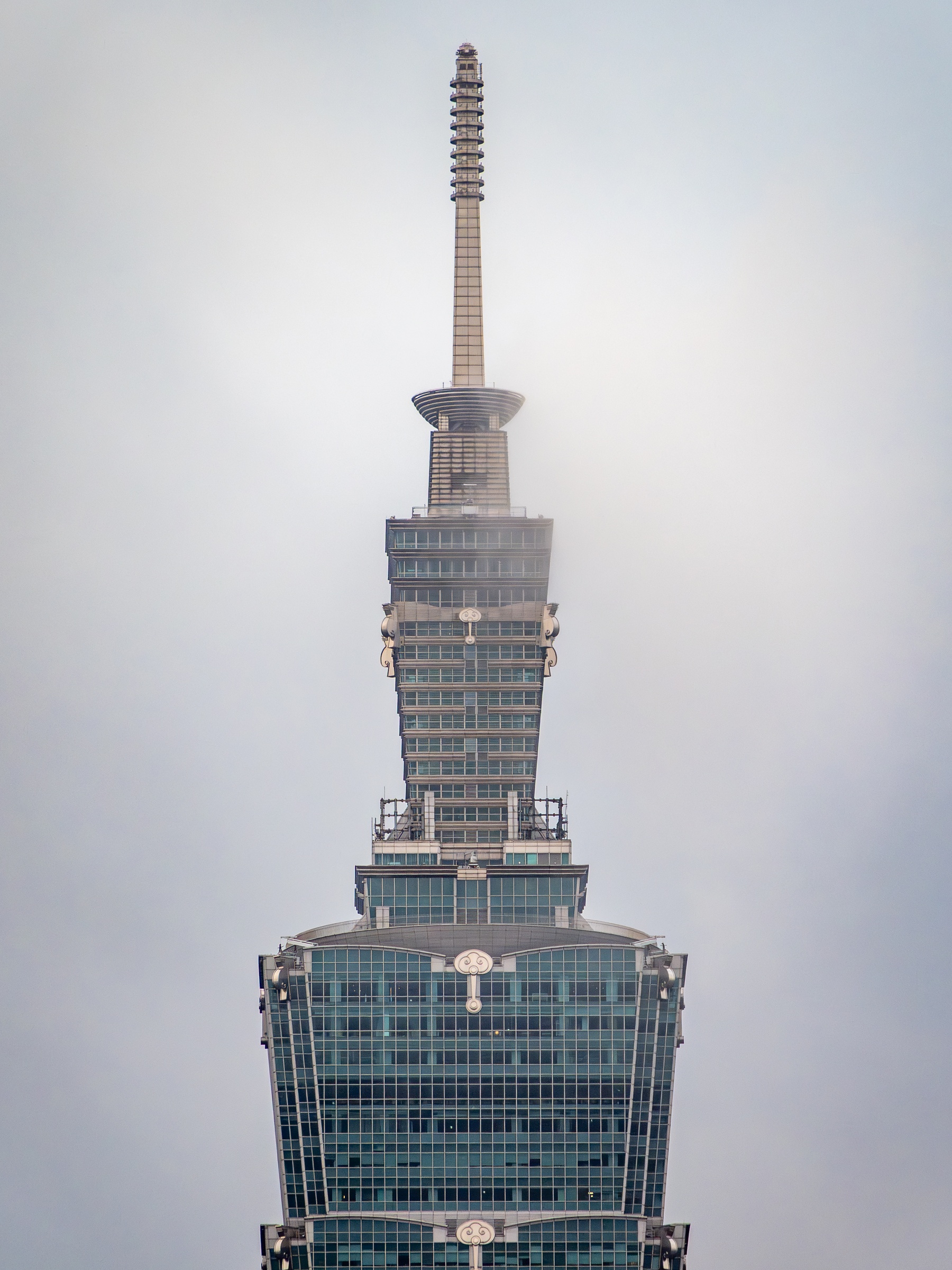 Taipei 101 tower rises against a cloudy, overcast sky.
