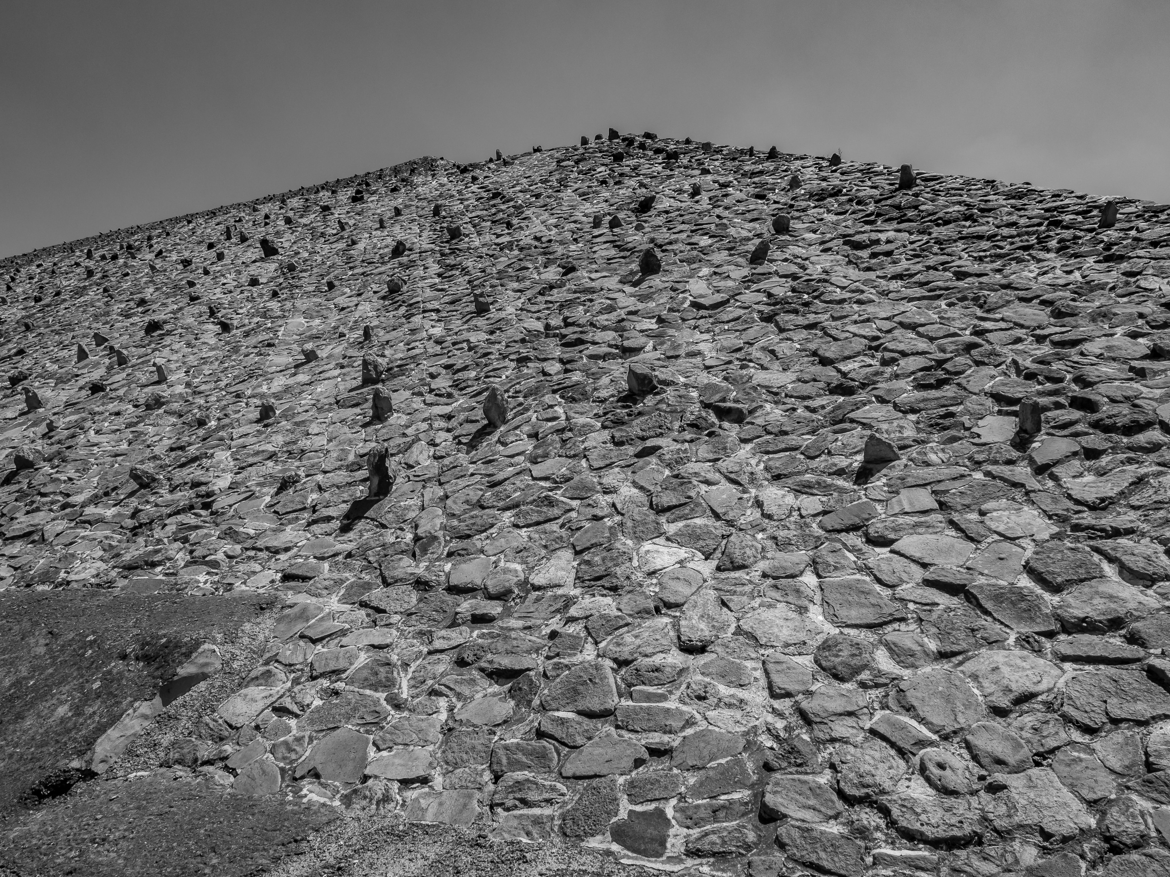 A large stone mound, covered in small rocks, rises against a pale sky.