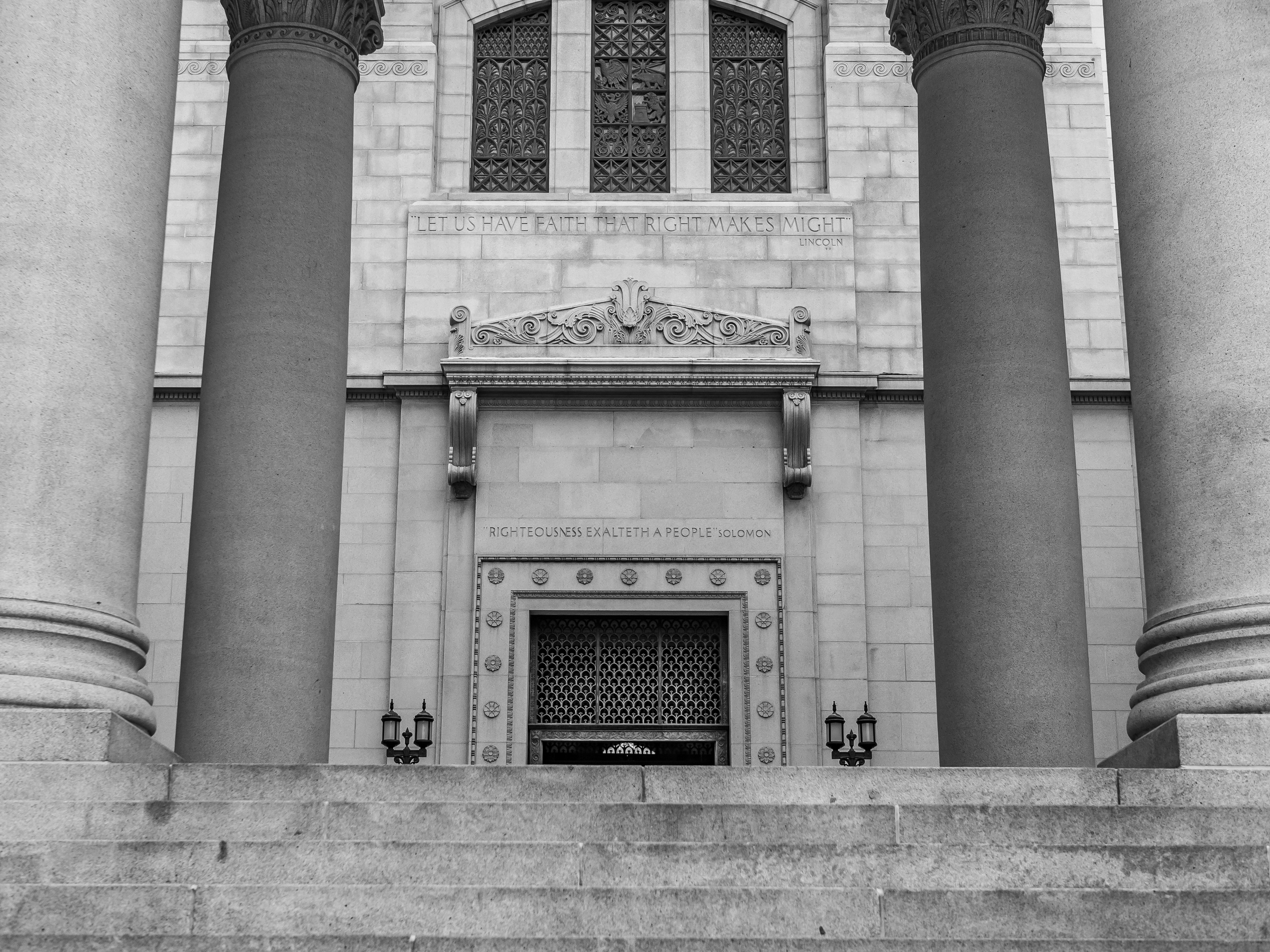 Monumental stone pillars and a doorway with ornate details frame the entrance to a grand building.