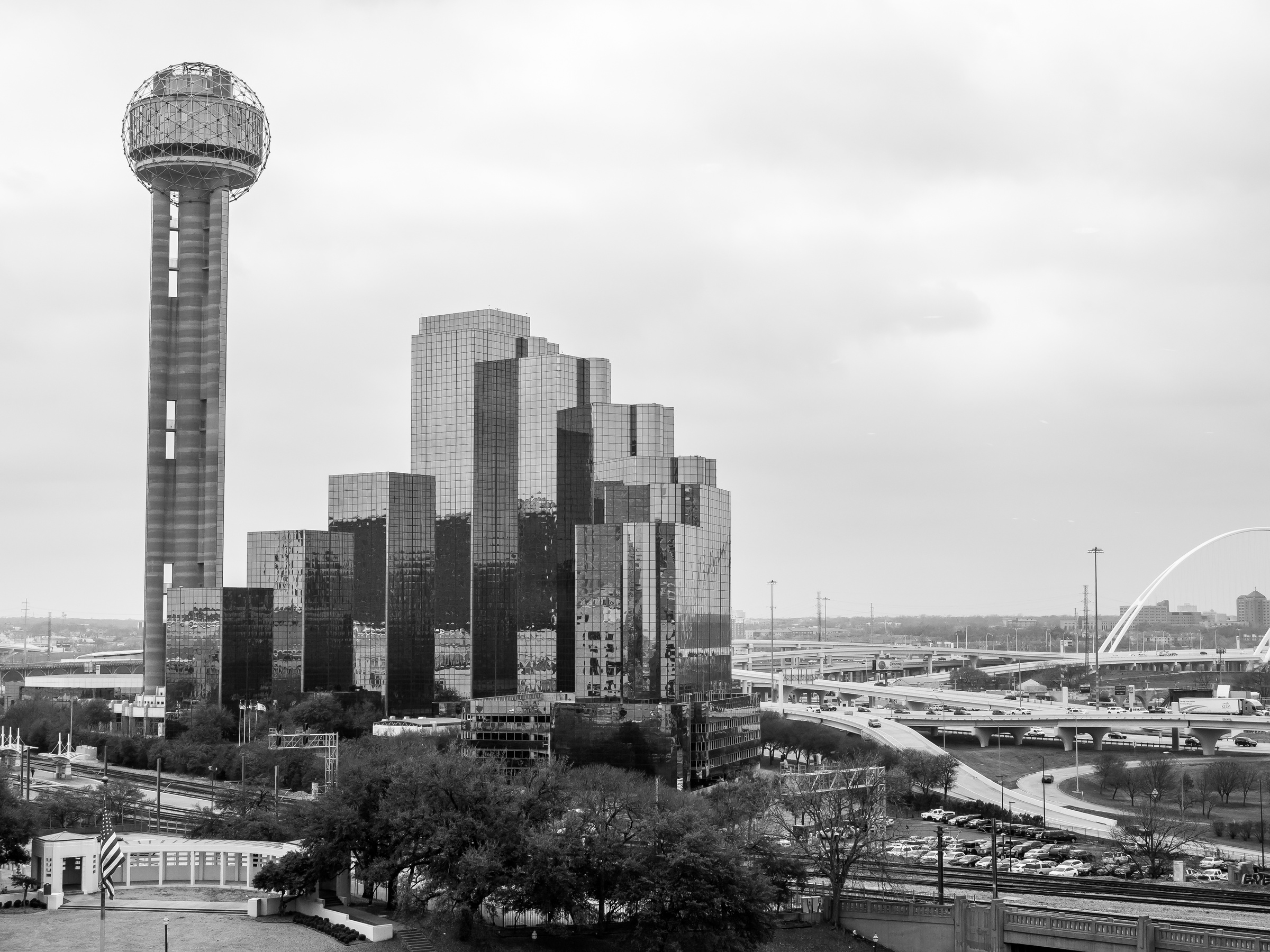 The Reunion Tower and surrounding buildings dominate a cityscape under an overcast sky.