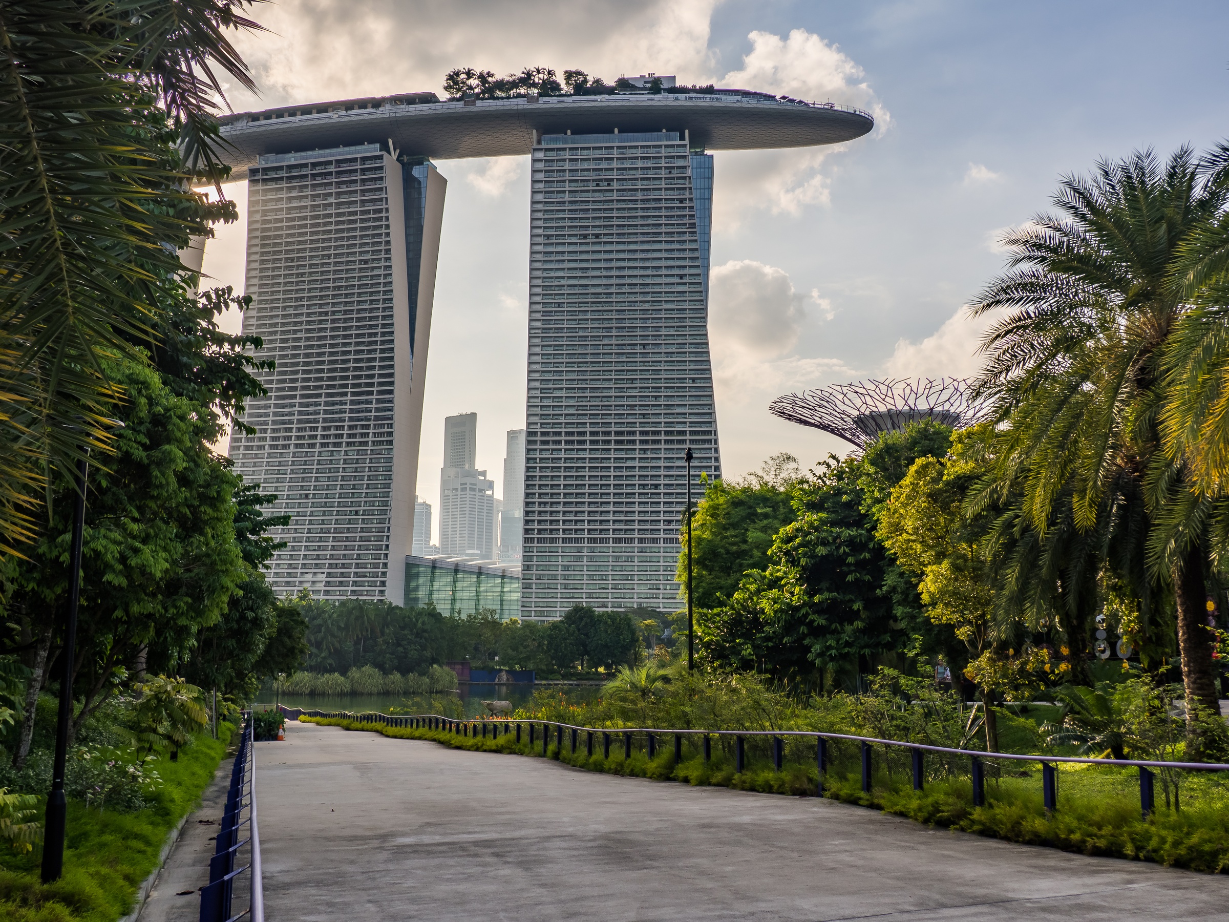 Two distinctive skyscrapers with a sky bridge connect them, set within lush greenery and overlooking Singapore's skyline.