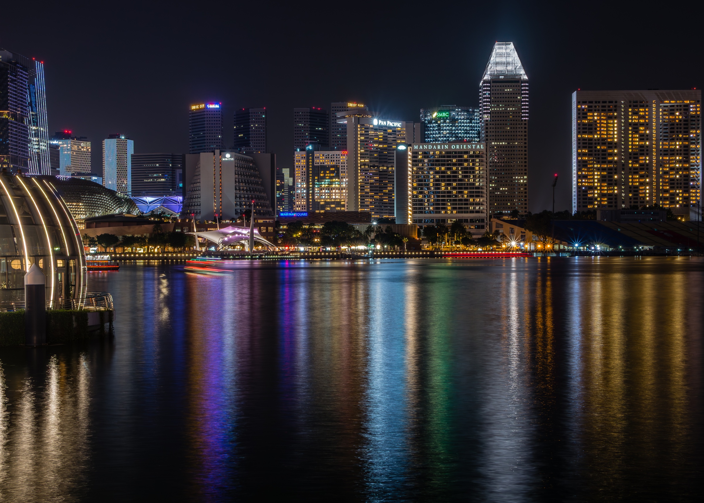 Singapore's illuminated skyline reflects in the calm waters of a river at night.