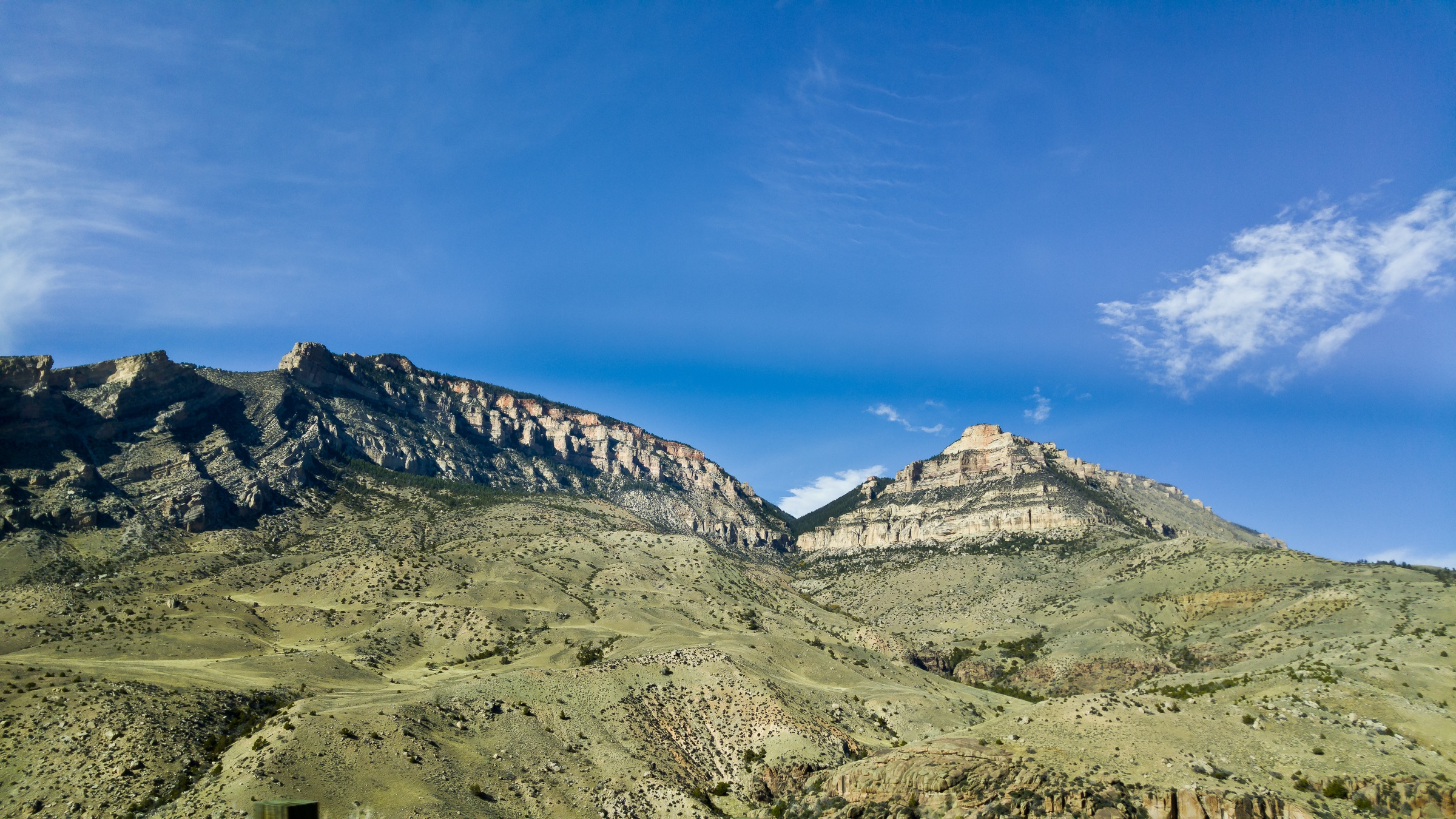 Rugged mountain peaks stand under a clear blue sky in an arid landscape.