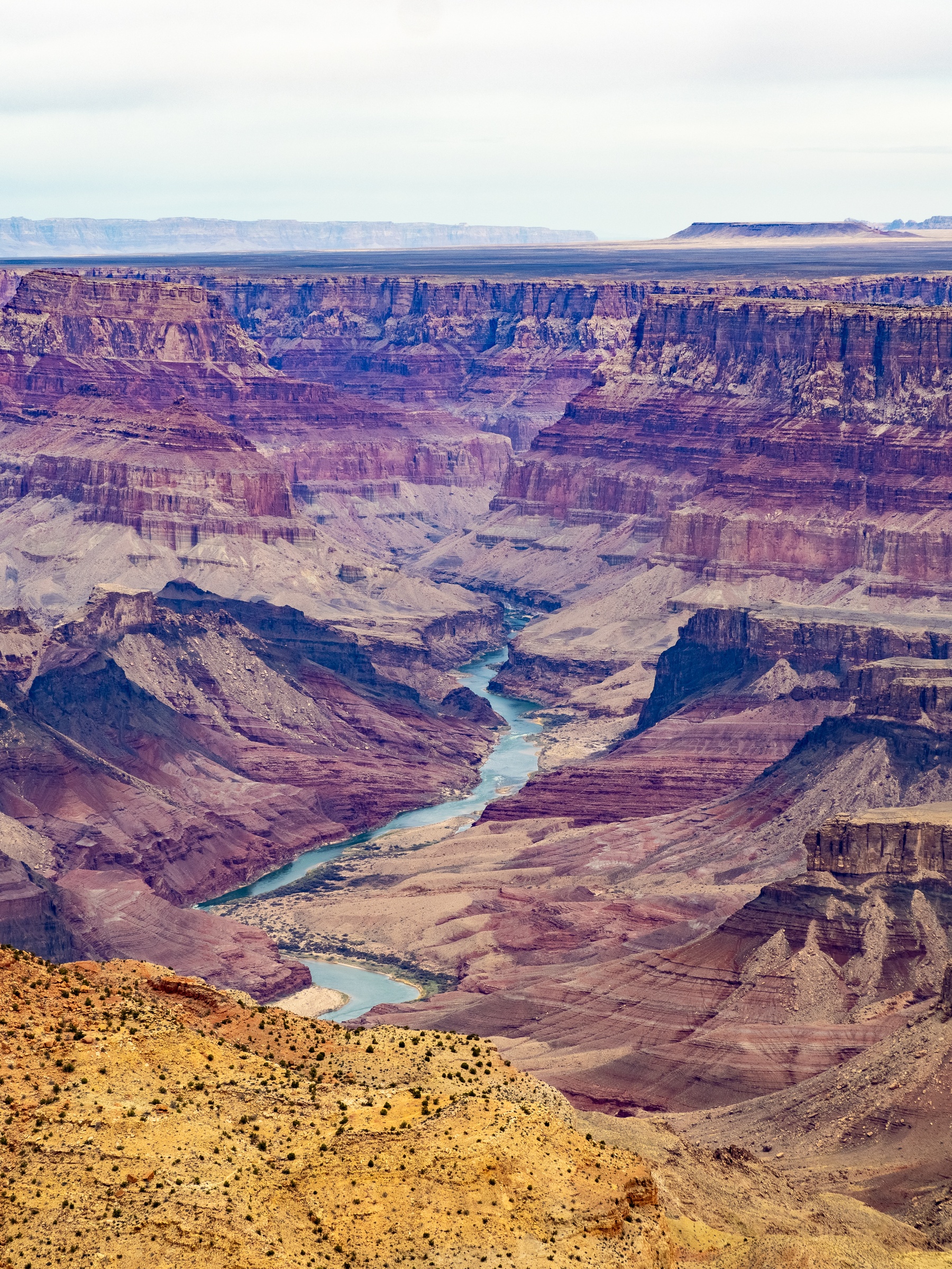 A river winds through the deep, layered red rock formations of the Grand Canyon.