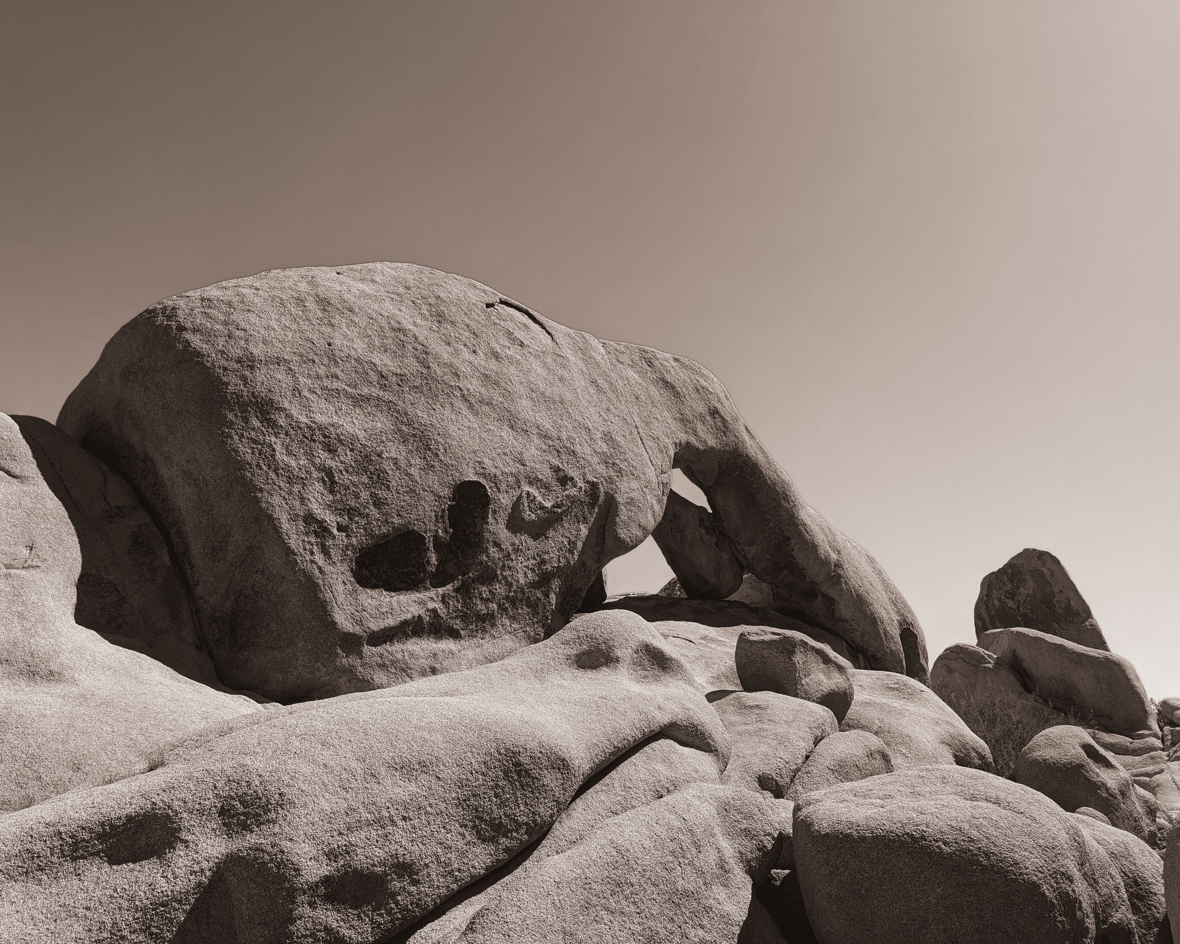 Large, smooth brown rock formations under a clear sky.