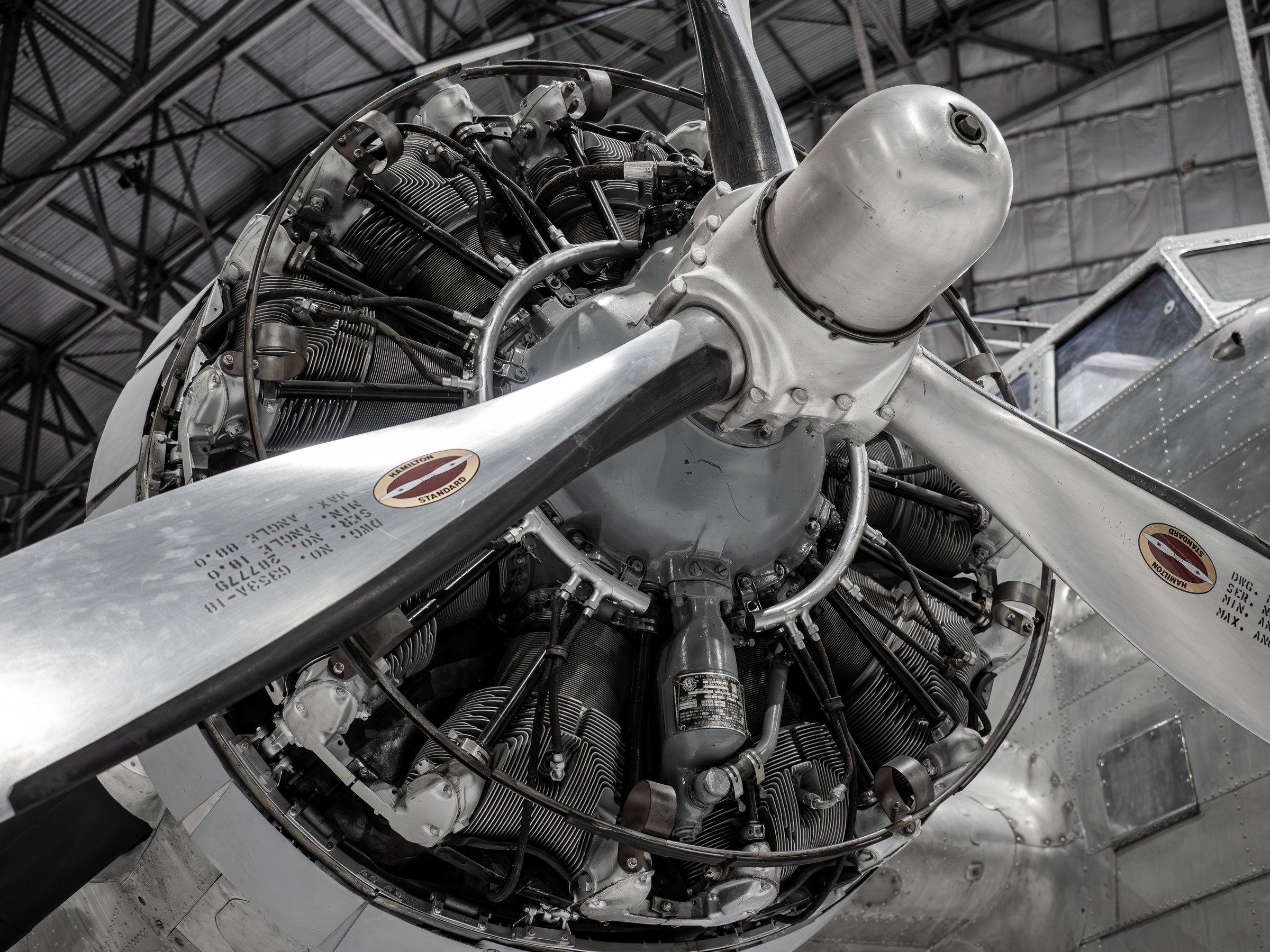 Vintage radial aircraft engine and propeller are displayed within a large hangar.