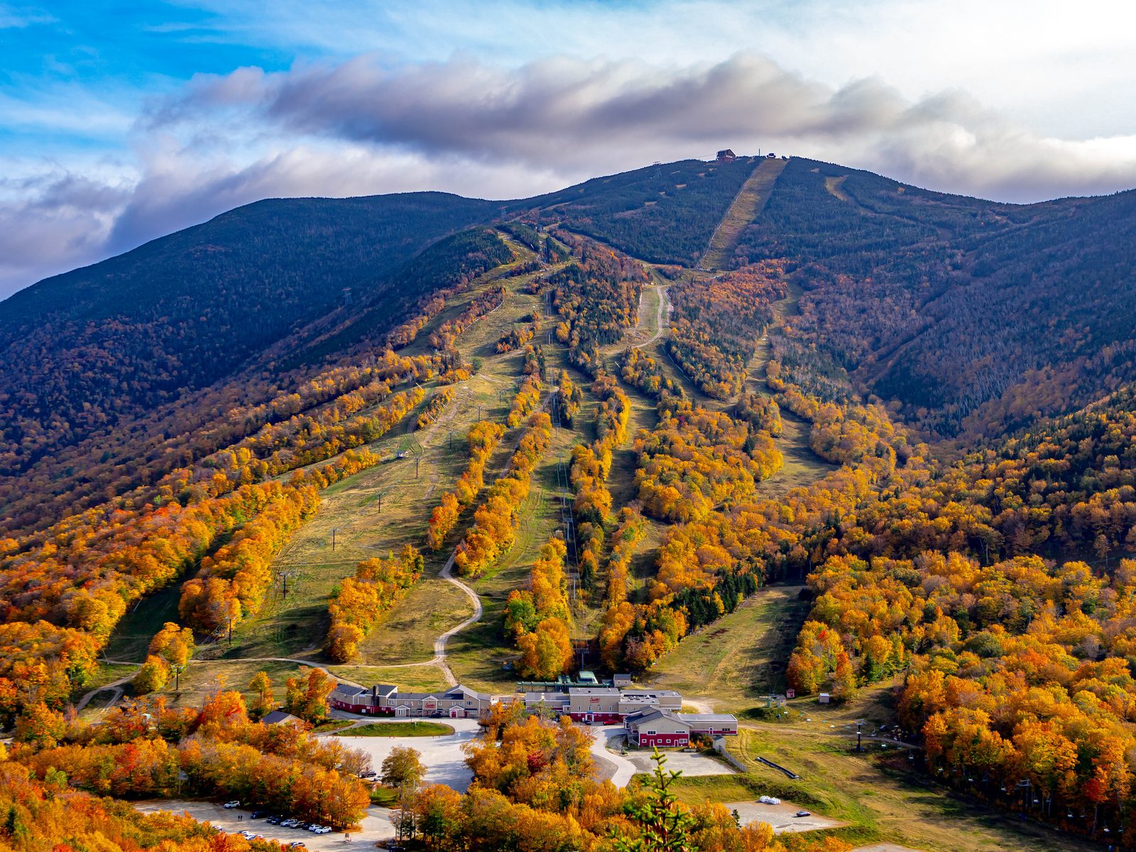 A ski hill in autumn colors with slopes carved through the forest.